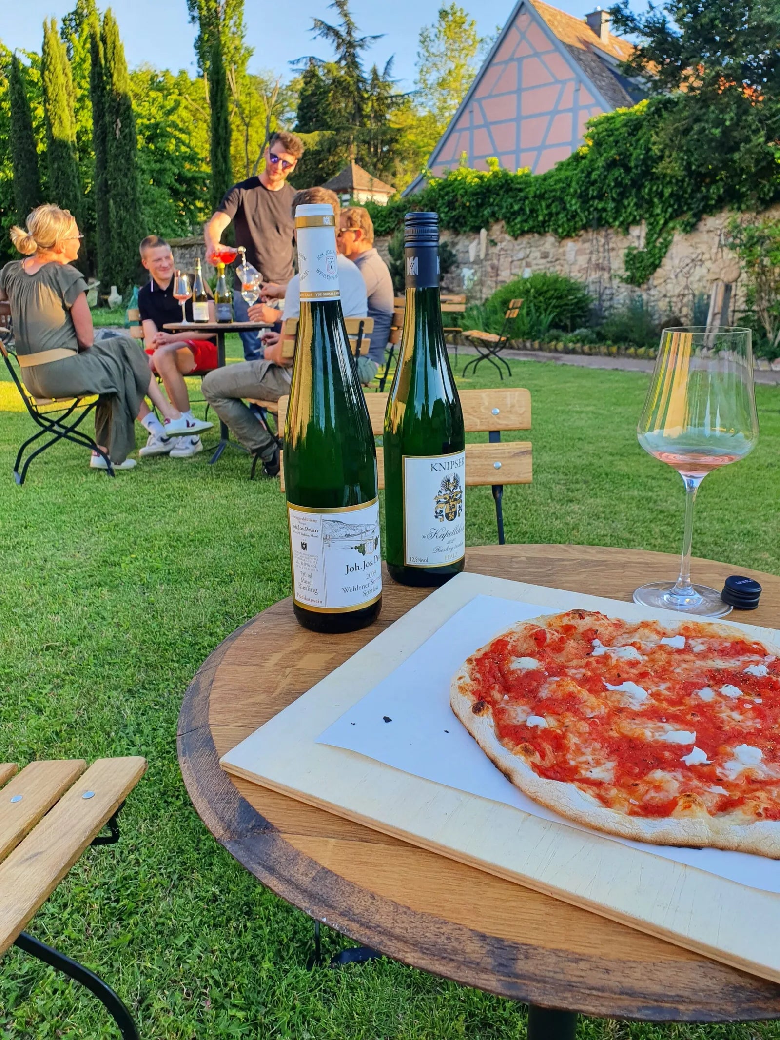 Gäste, Wein und Flammkuchen an einem Sommerabend im Garten