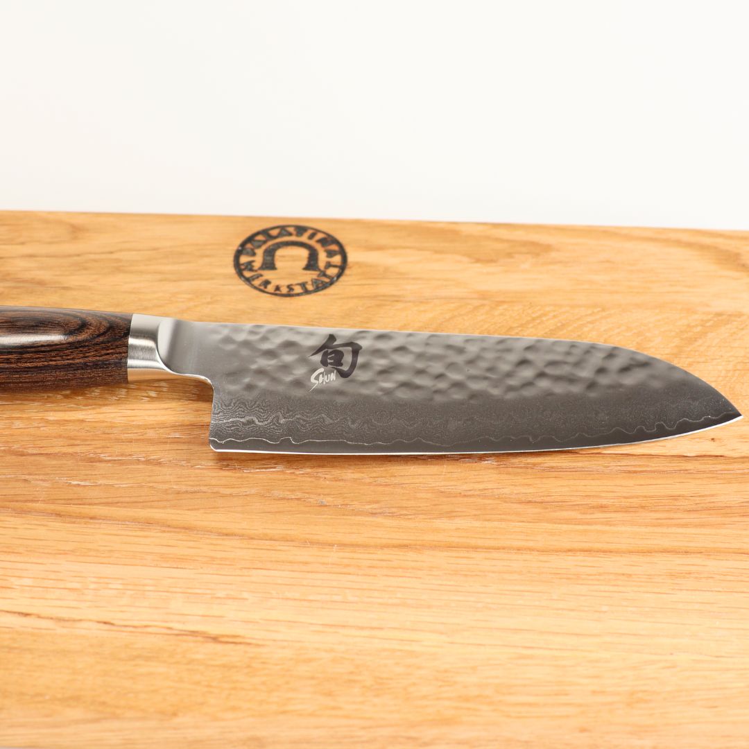 Das Kai Shun Premier Tim Mälzer TDM-1727 kleines Santoku (14 cm Klinge) liegt auf dem 30x20 cm Schneidebrett und verkörpert die Präzision eines japanischen Küchenmessers.